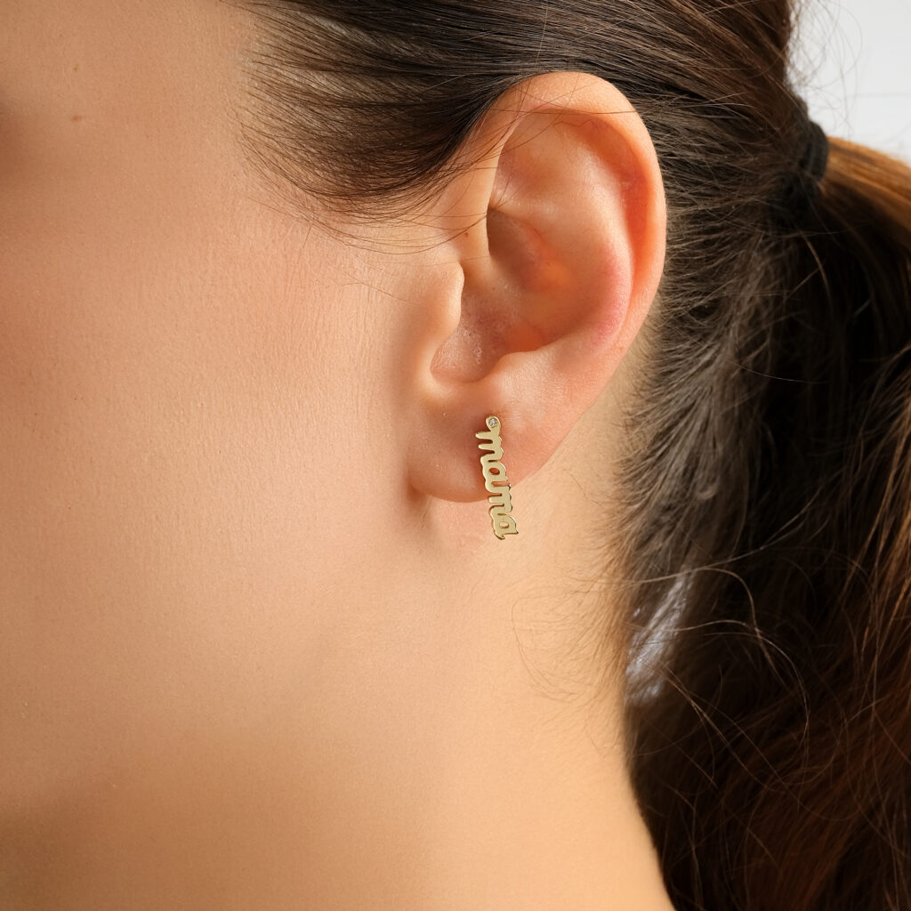 Mama Script Single Earring — the word mama in yellow gold script with a diamond accent, worn on ear